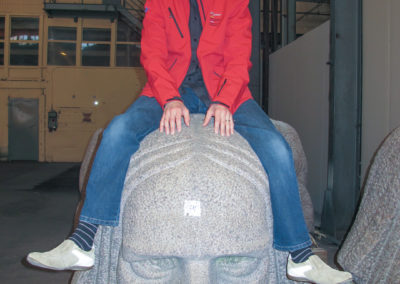 Kiviseppämestari istumassa Suomen kuuluisimman kivimiehen pään päällä